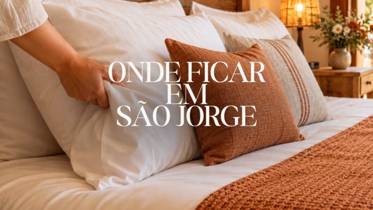 Imagem ilustrativa de cama aconchegante com almofadas terracota e decoração rústica, com o título “Onde ficar em São Jorge”.